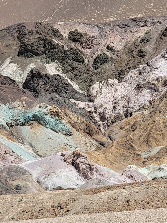 Artist's Palette formation in Death Valley, with the famsou black, purple, red, pink, green, yellow, and white coloration in various bands and piles of rock.