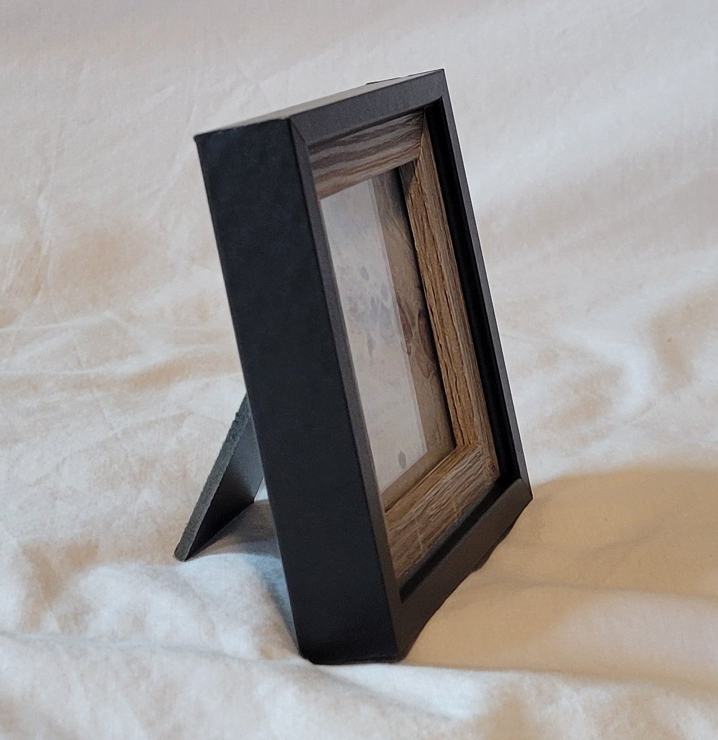 A mostly side-on view of the frame, demonstrating the stand it can use to rest on a desk surface. The art is largely obscured, but some of the purple bubbles are visible in the lavender square.