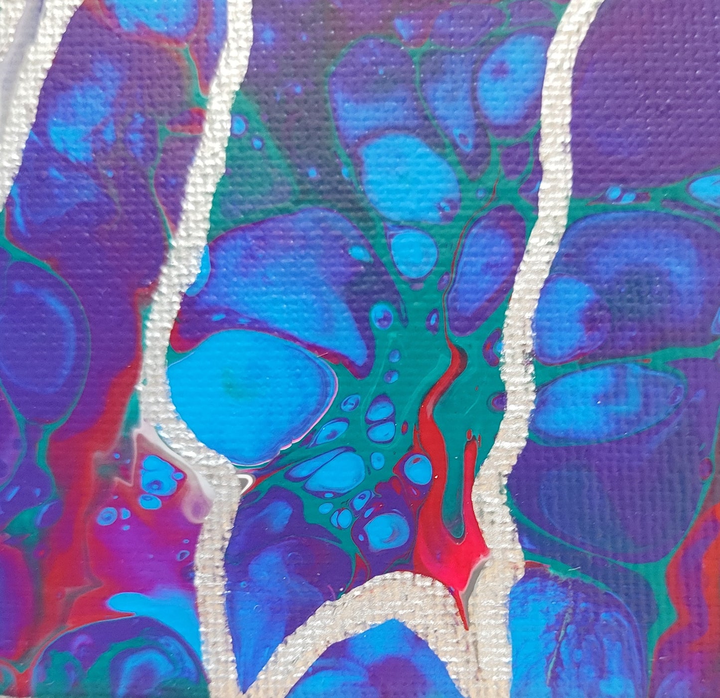 Close-up detail of the fluid pour showing blue bubbles outlined first in purple and then further in green with veins of silver and magenta.