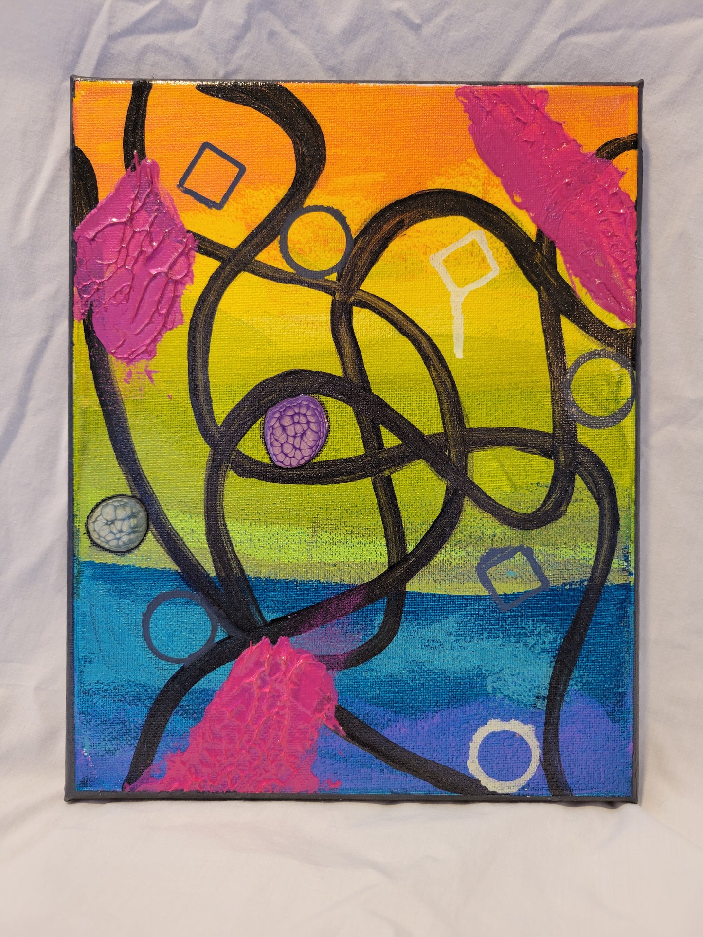Black swooping lines curve, arc, and intersect over a canvas painted in a near rainbow of shimmering orange, yellow, green, teal, blue, and purple. There are outlines of squares and circles scattered throughout, some more neat and tidy than others, some filled with alkyd oil. There are glossy textured swipes of pink gel at the edges of the canvas.