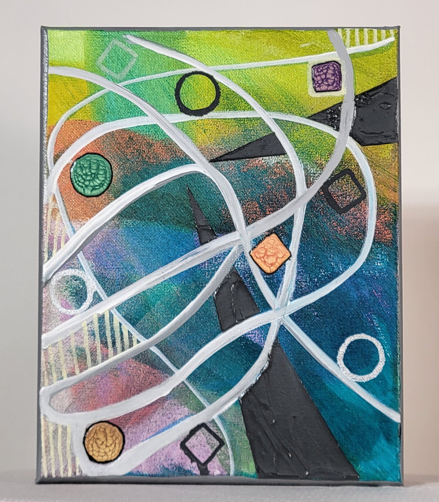 Against a colorful background of yellow, green, orange, teal, blue, and pink, a white and gray series of lines arc, swoop, and intersect all over the canvas. In a couple of areas between the lines and the edge of the canvas, off-white vertical lines fill in the space. Circles and squares in a range of tidy and messy punctuate the canvas, some are filled with alkyd oil. Two triangular wedges of deep gray textured paint intrude from the edges of the canvas to nearly touch toward the center.