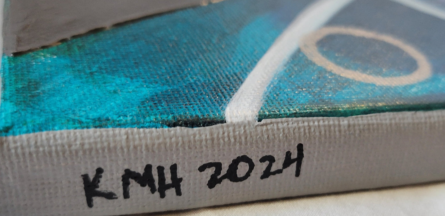The silver painted edge of the canvas with "KMH 2024" written in black. A blue and teal blend of paint is visible on the front.