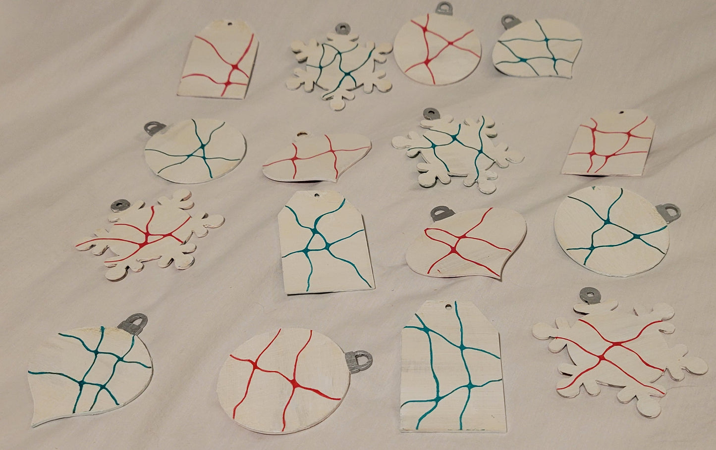 All 16 ornaments (4 sets of 4) rest on a white background. They all feature a unique detail of line work in either red or green.