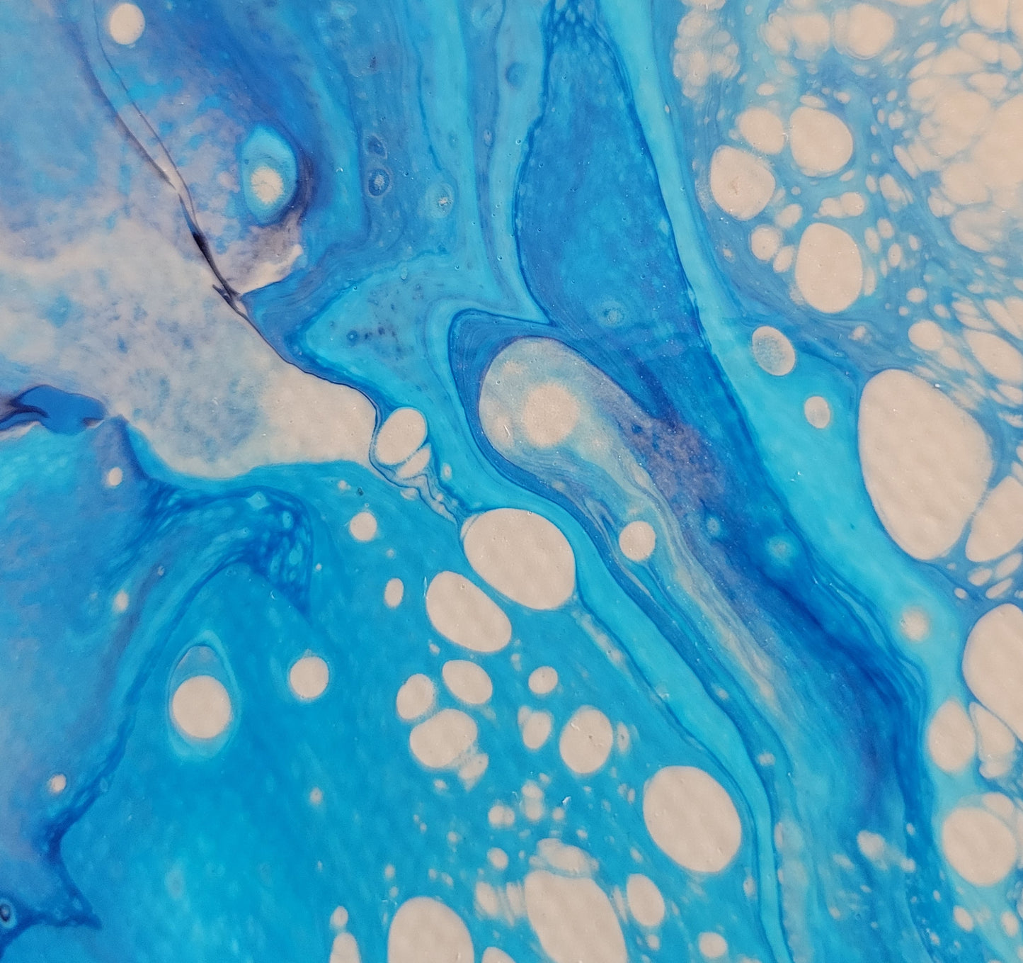 Closeup detail of the canvas showing the layering of the bright turquoise and darker sky blues with bubbles of sandy brown.