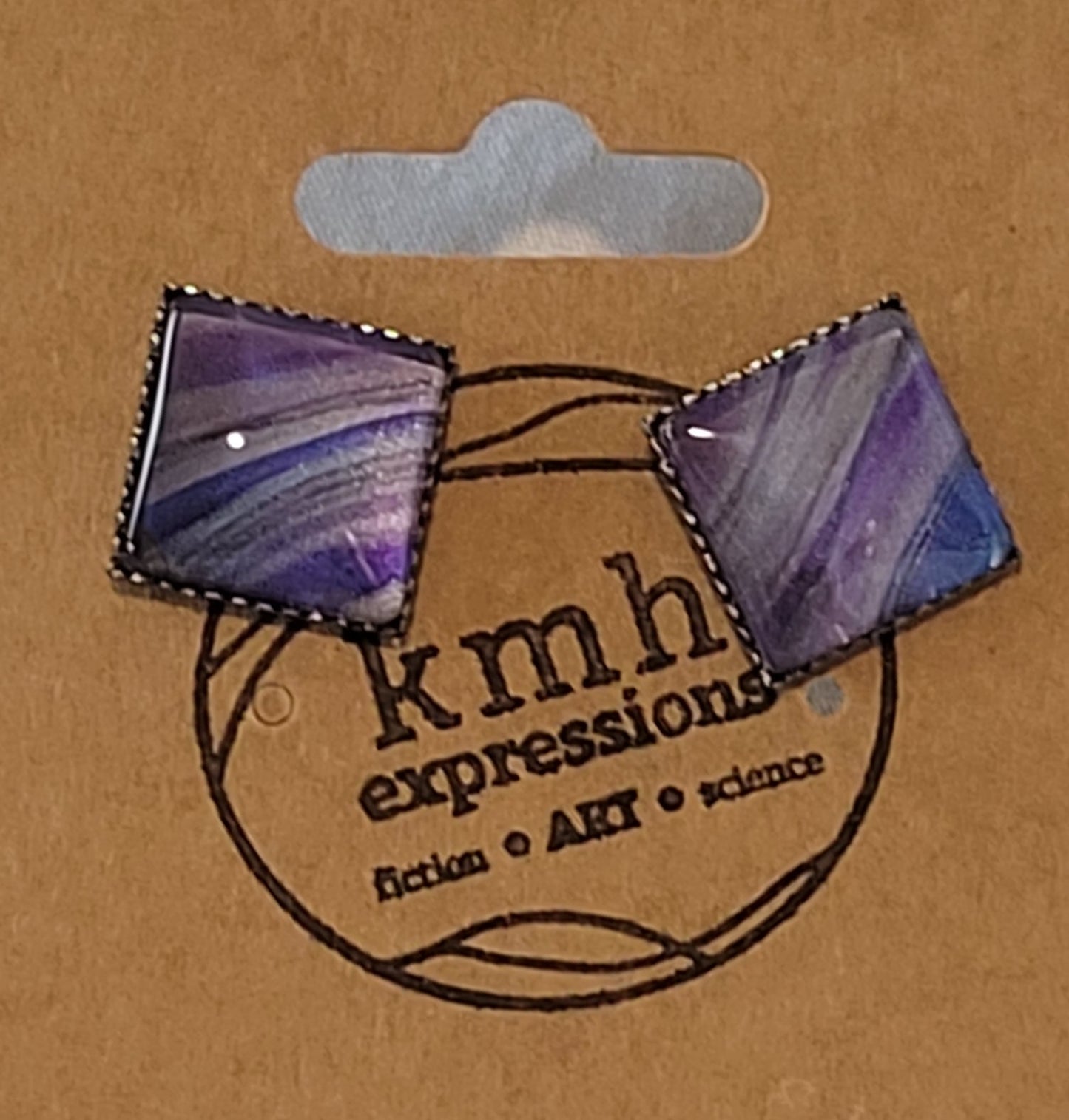 Banded gentle arcs of silver, purple, space gray, and dark blue in a simple black stainless steel stud on a card stamped with the kmh expressions logo.