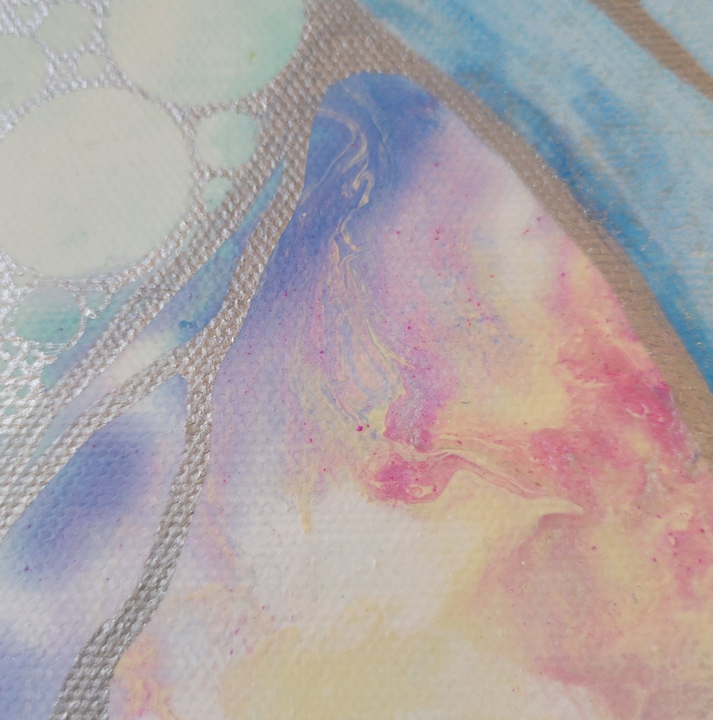 Close-up detail of the fluid acrylic intersection of the hourglass, showing the intermixing swirls of violet, pink, and peach with the silver line work and circles framing it.
