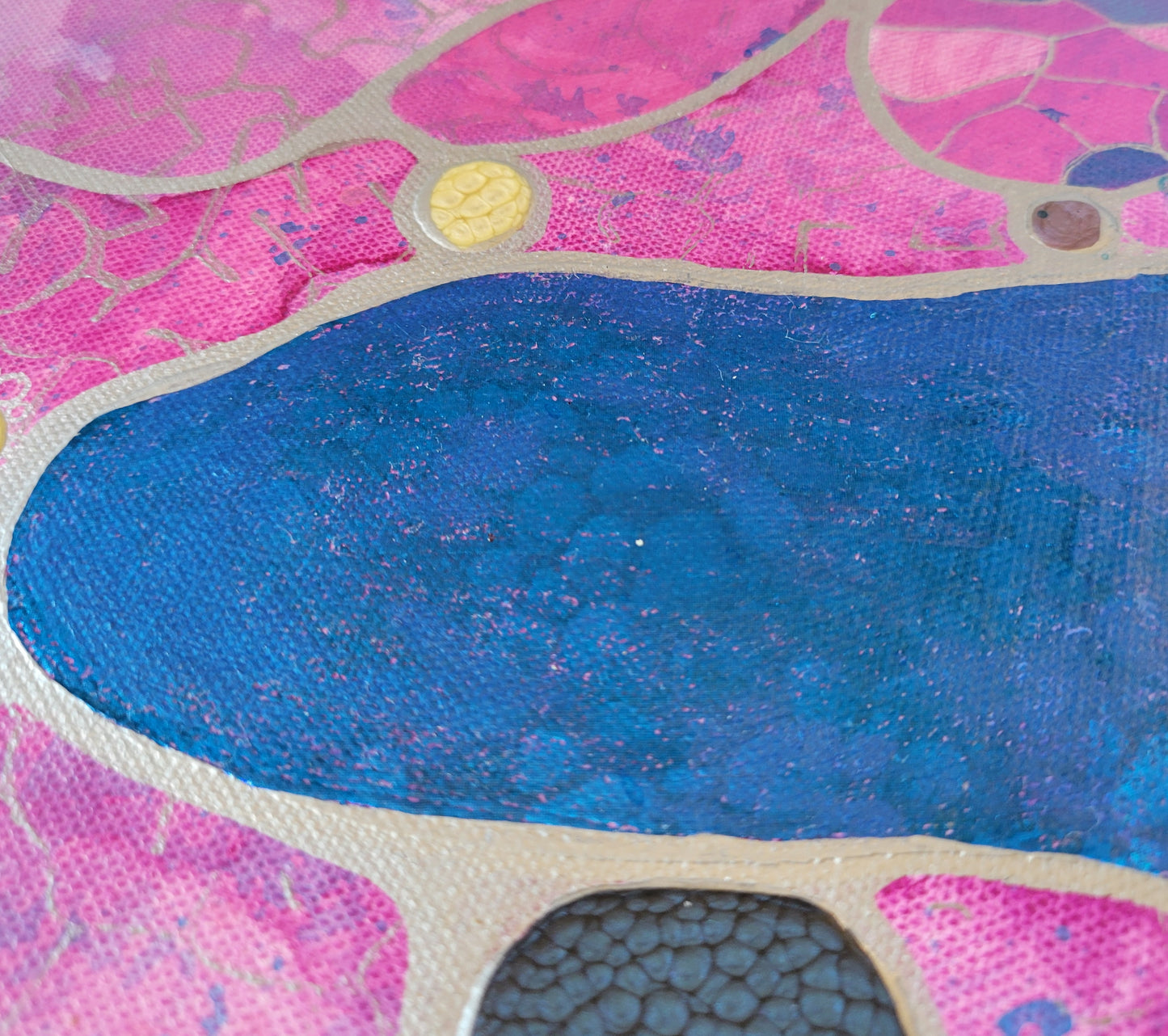 Close-up of one of the blue amoeba shapes, highlighting the blue pebble foil. The gradations of the pink background can be seen along with three drops of alkyd oil in cream, purple, and dark blue.