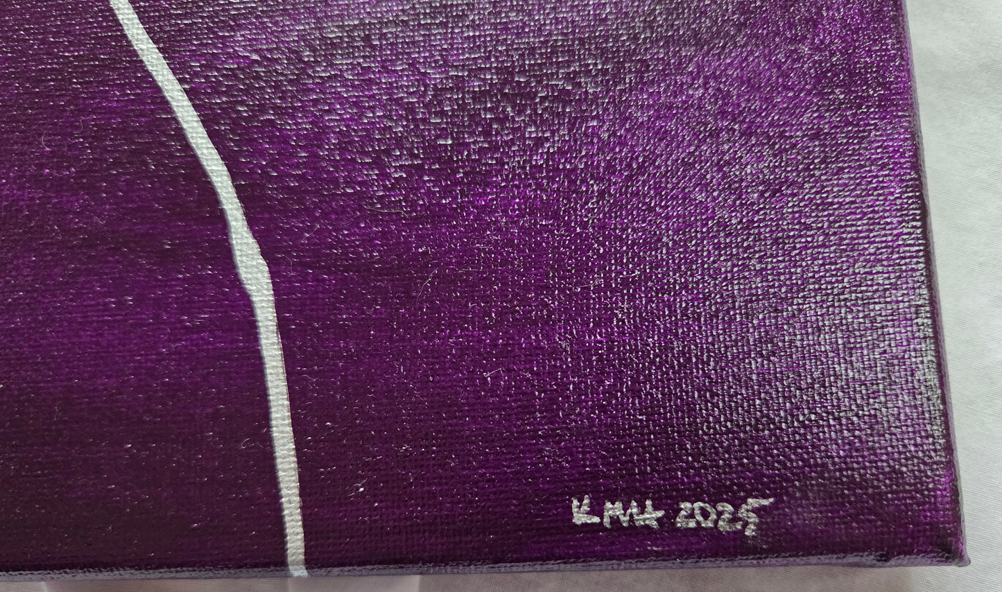 Close-up detail of the purple band of the asexual pride flag showing a thick silver line and the artist's initials and year of completion in silver in the lower right corner.