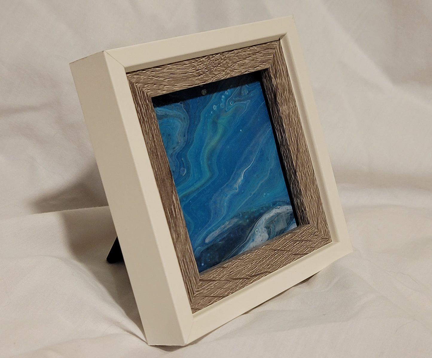 An angled view of the frame, demonstrating the stand it can use to rest on a desk surface. From this angle, more of the gradations of blue shades can be seen.