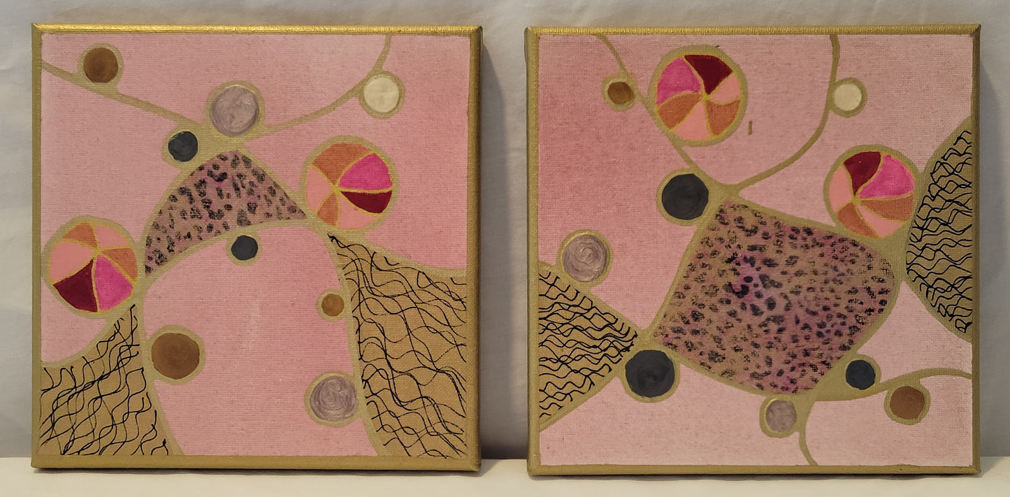 Two canvases rest on a white background. They both have light pink soft backgrounds, distressed with faint gold spots. Gold neurographic lines thread across the canvases. Three of the intersecting spaces on each canvas are painted gold. The central spaces are covered with a pink leopard print foil. The edge spaces have black squiggly lines. Multi-colored balls in pinks and golds flow along the lines along with pink, black, gold, and white alkyd oil circles.