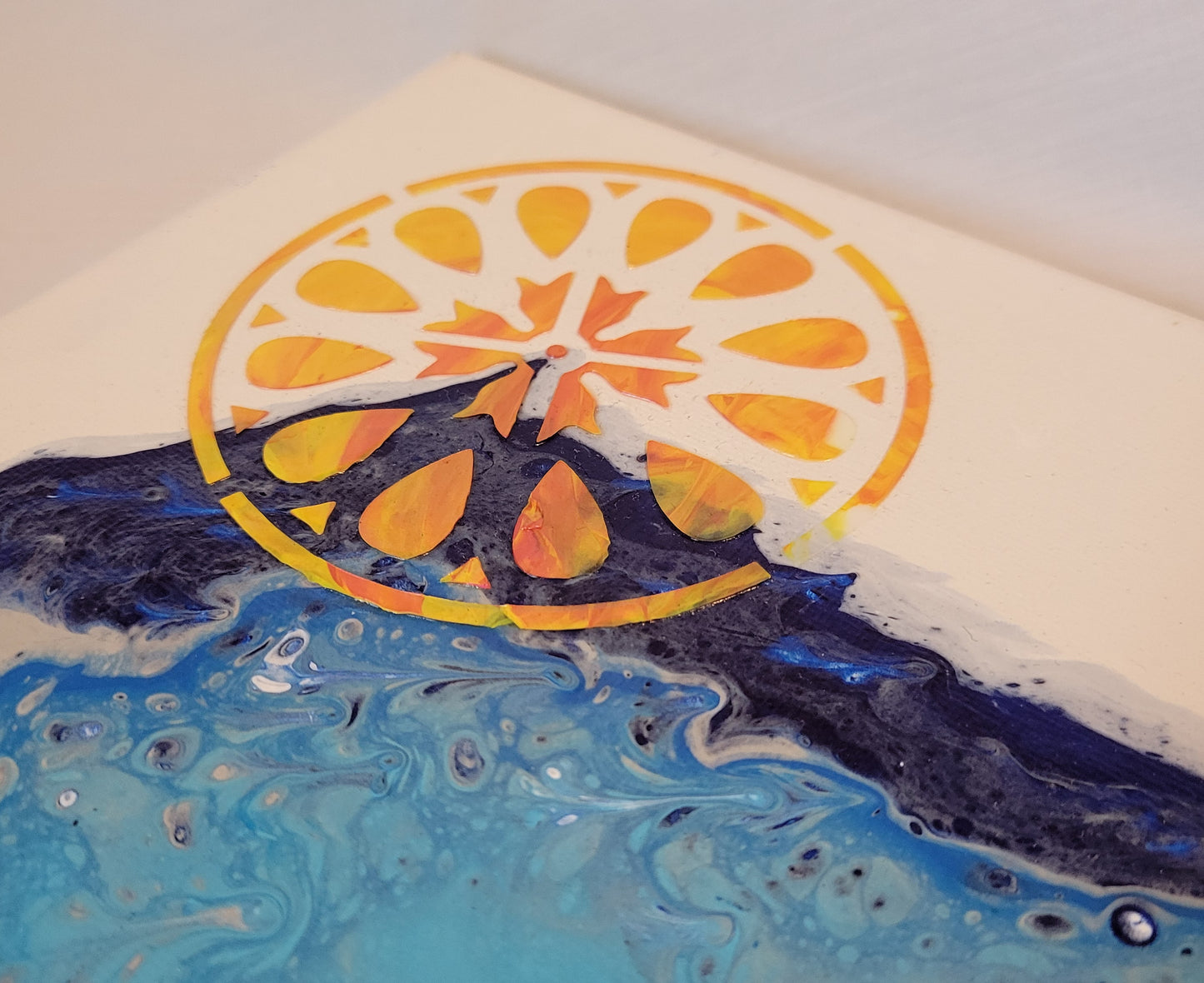 Angled photo from an angle that shows the textured dimension of the orange and yellow stylized sun.