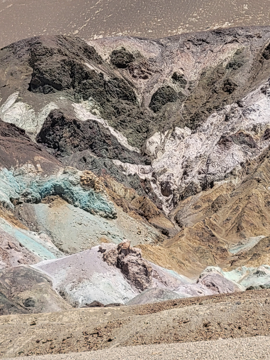 Artist's Palette formation in Death Valley, with the famsou black, purple, red, pink, green, yellow, and white coloration in various bands and piles of rock.