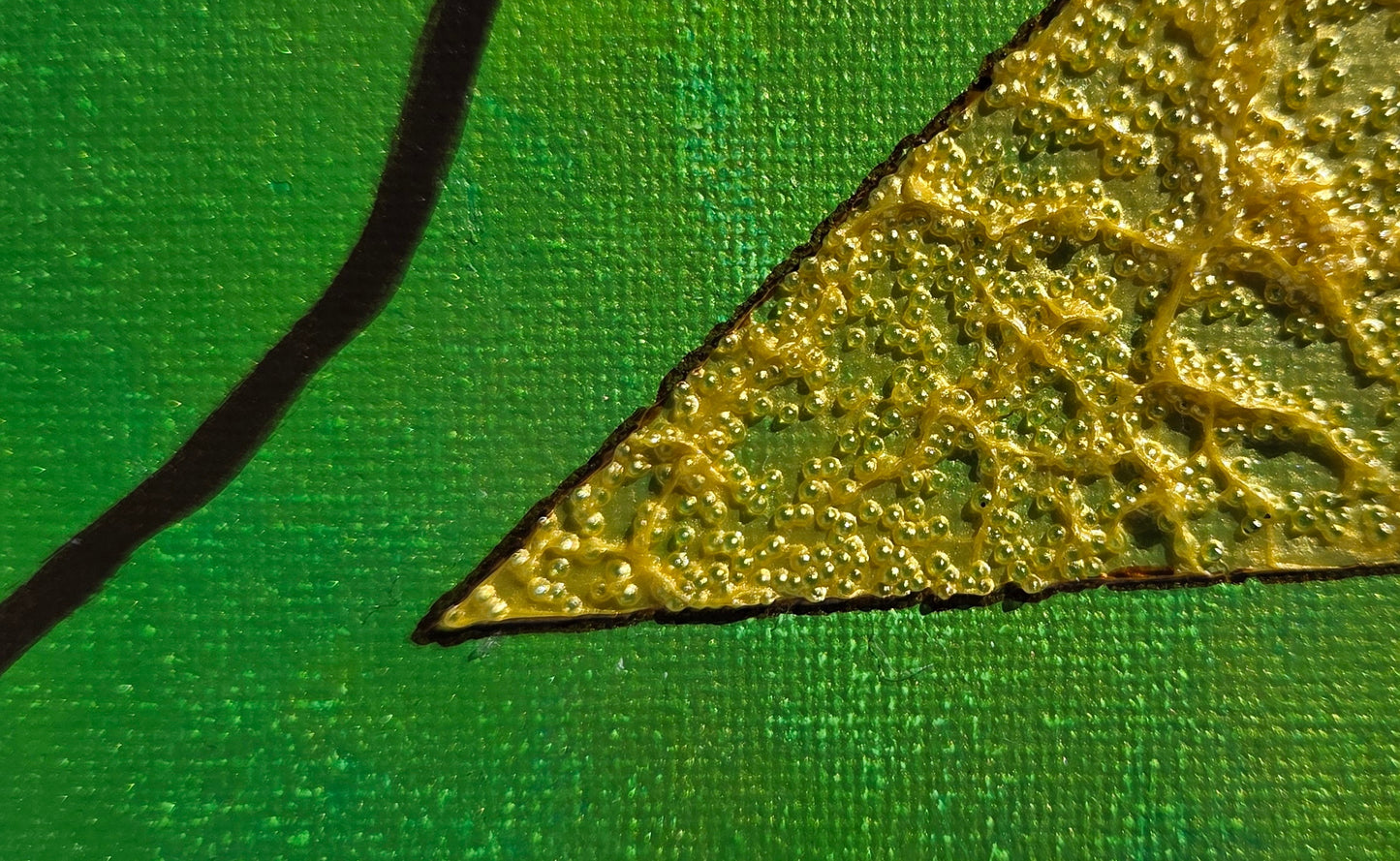 Close-up detail of the gold glass bead triangle encroaching on the variegated green-gold background with an arc of a brown vine-like line.