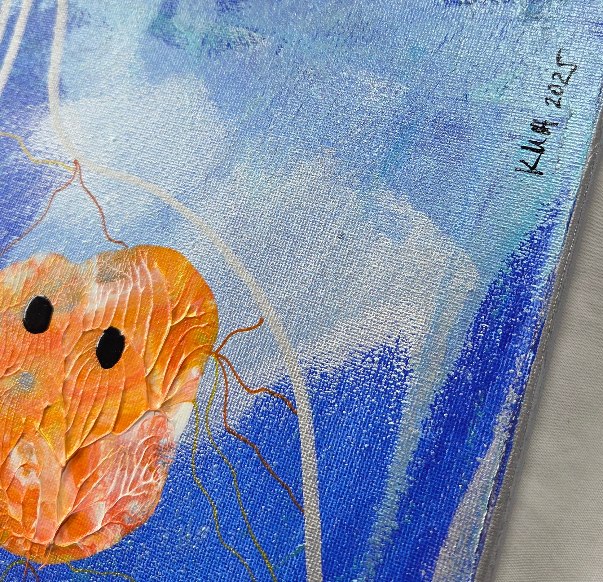 Close-up of the bottom right corner of the canvas, showing more koi blobs, under and around the frothy blue sea. The artist's initials and date of completion (KMH 2025) are written in black.