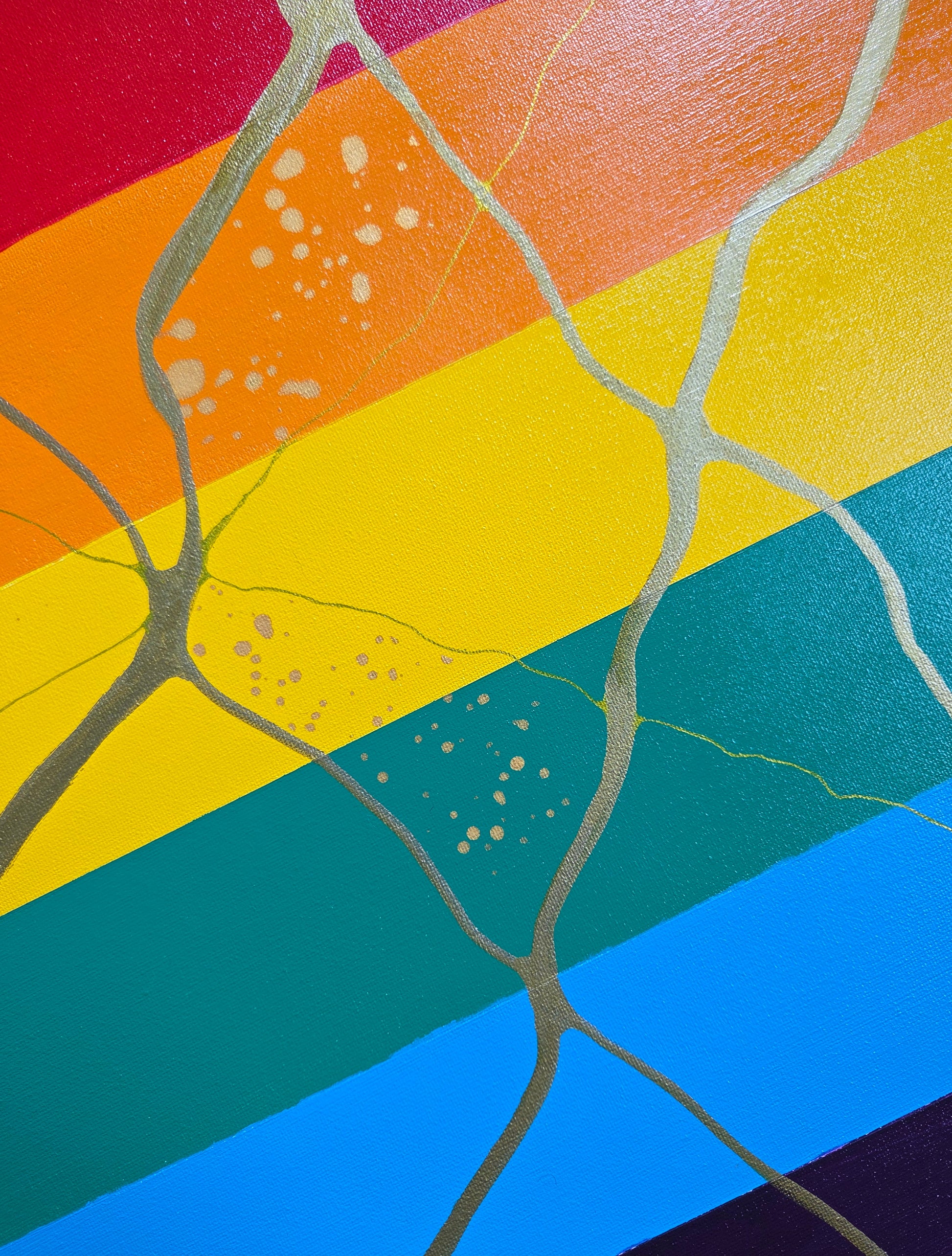 Detail of the anatomical heart-like shape outlined in gold lines and speckled with gold ink overlaid against the pride flag.